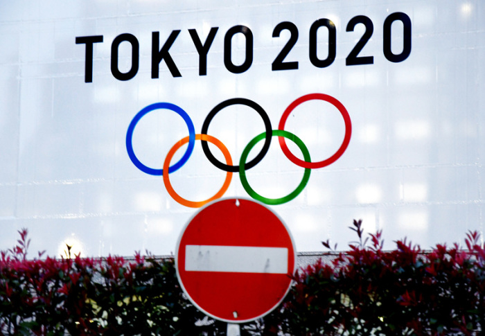 Das Logo für die Olympischen Sommerspiele Tokyo 2020 sind hinter einem Straßenschild zu sehen.  Foto: Ramiro Agustin Vargas Tabares/Zuma Wire/dpa