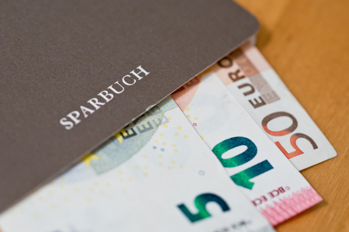 Euro-Geldscheine liegen in einem Sparbuch. Foto: Daniel Karmann/Dpa