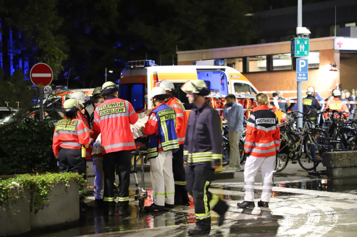 Feuerwehrleute und eine Notärztin stehen nach einem Brand im Marien Hospital vor dem Krankenhaus um einen Patienten auf einer Liege herum. Foto: Sascha Rixkens/Dpa