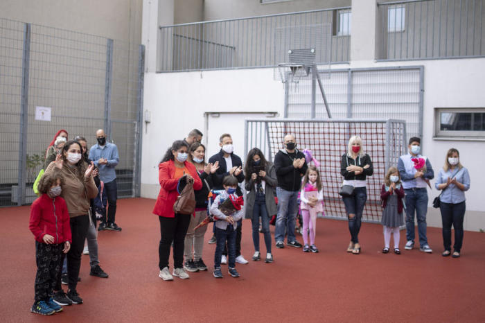 Schülerinnen und Schüler mit Schutzmasken warten an ihrem ersten Schultag vor einer Wiener Volksschule neben ihren Betreuern auf dem Spielfeld. Foto: epa/Christian Bruna