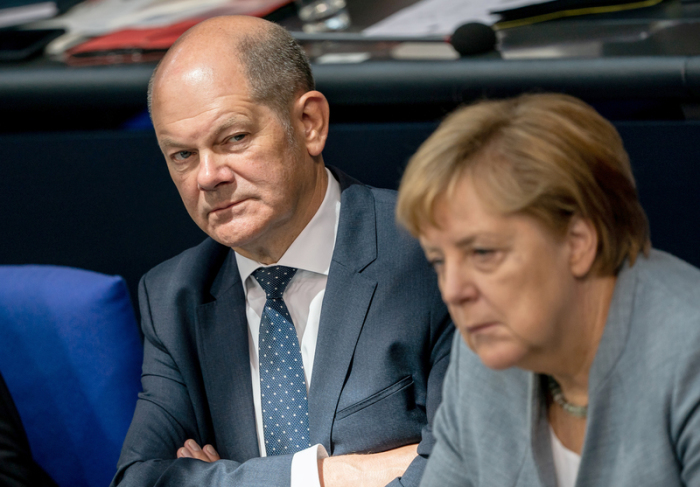 Olaf Scholz (SPD), Bundesminister der Finanzen, verfolgt neben Bundeskanzlerin Angela Merkel (CDU), im Bundestag die Debatte zu Beginn der Haushaltswoche. Foto: Michael Kappeler/Dpa