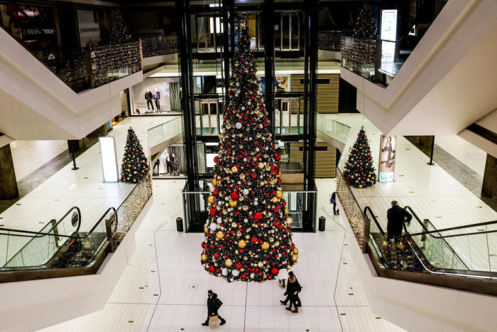 Einkäufer gehen an einem großen Weihnachtsbaum in einem Einkaufszentrum in Berlin vorbei. Foto: epa/Filip Singer