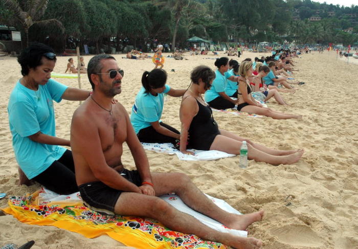 Ausländische Urlauber genießen am Strand auf Phuket in Vor-Corona-Zeiten eine Massage. Foto: epa/Yongyot Pruksarak