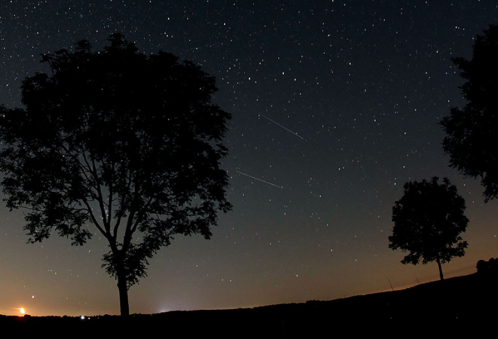 Sternschnuppen der Perseiden (Bildmitte) sind am in der Nähe von Nettersheim in der Eifel am Nachthimmel zu sehen. Foto: Oliver Berg/Dpa