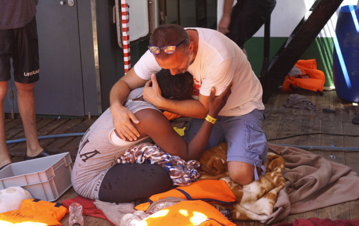 Ein Besatzungsmitglied des spanischen Rettungsschiffes «Open Arms» von der Hilfsorganisation Proactiva Open Arms tröstet einen Migranten. Foto: Francisco Gentico/AP/dpa
