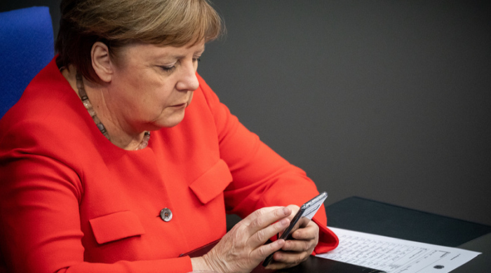 Bundeskanzlerin Angela Merkel (CDU) tippt nach ihrer Regierungserklärung im Bundestag in ihr Smartphone. Foto: Michael Kappeler/dpa
