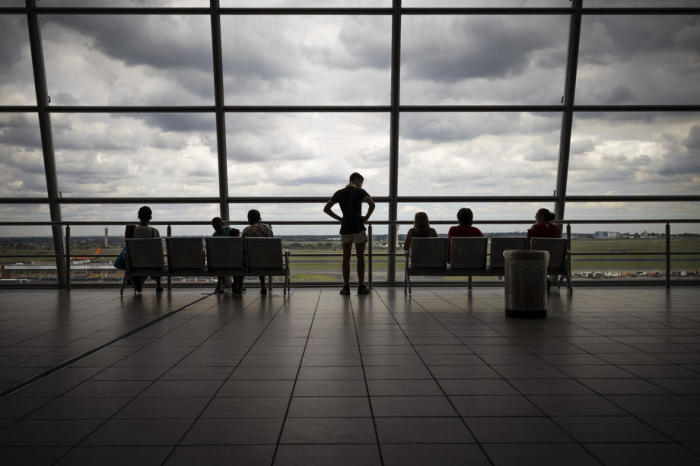 Fluggäste sitzen auf der Aussichtsplattform des internationalen Flughafens OR Thambo und beobachten die startenden und landenden Flugzeuge. Foto: epa/Kim Ludbrook