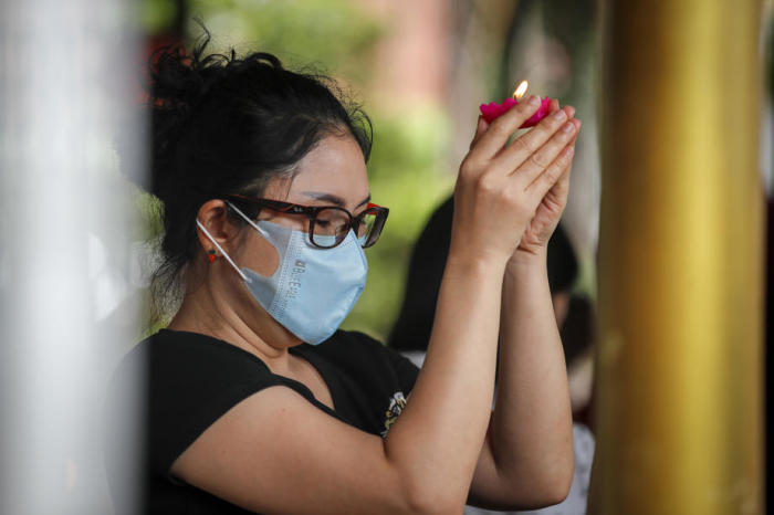 Eine Buddhistin schützt sich beim Tempelbesuch mit einer Gesichtsmaske. Foto: epa/Diego Azubel