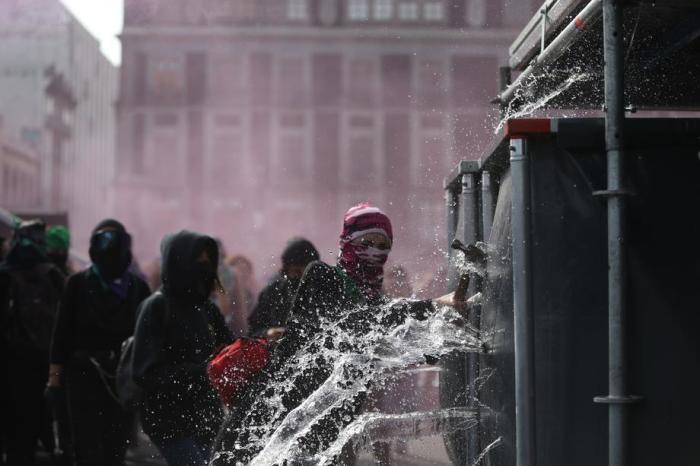 Vermummte weibliche Demonstranten attackieren und durchlöchern einen Wassertank gegen ihre gegen geschlechtsspezifische Gewalt. Foto: epa/Sashenka Gutierrez