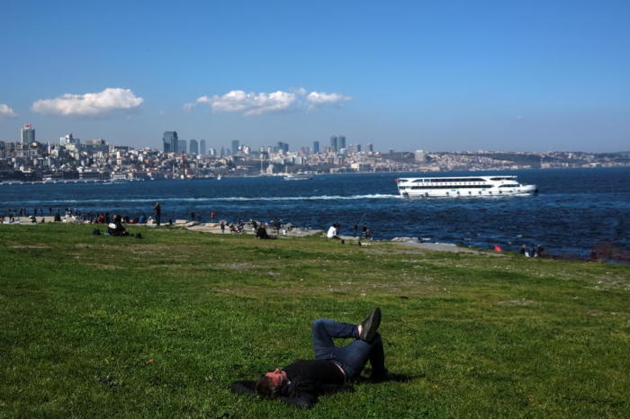 An einem sonnigen Tag vor der Abriegelung in Istanbul schläft ein Mann in der Nähe des Bosporus (Hintergrund). Foto: epa/Sedat Suna