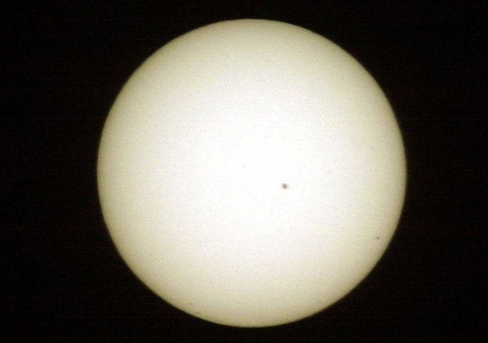 Der Planet Merkur ist am 07.05.2003 rechts unten als winziger schwarzer Punkt vor der Sonne zu sehen, in der Mitte ein Sonnenfleck. Foto: Stephan Jansen/Dpa