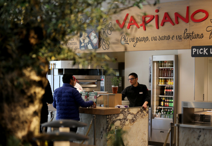 Ein Mitarbeiter bedient in einer Filiale der Restaurantkette Vapiano einen Kunden. Foto: Oliver Berg/Dpa