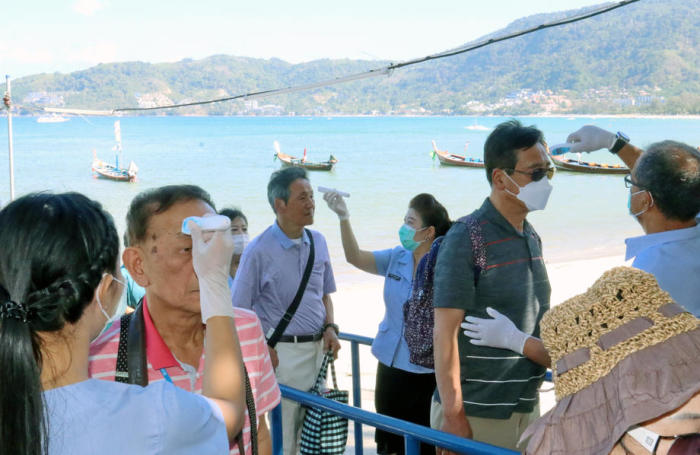 Ein Mitarbeiter des Gesundheitsministeriums misst die Temperatur ankommender Passagiere des Kreuzfahrtschiffes „Quantum of the Seas“ auf Phuket. Foto: epa/Yongyos Pueksarak