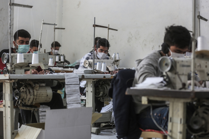 Arbeiter tragen Gesichtsmasken, während sie in einem kleinen Labor arbeiten. Foto: Anas Alkharboutli/Dpa