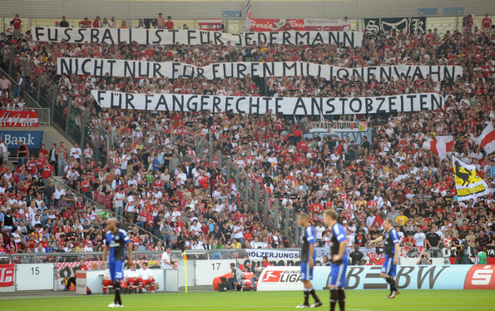 Stuttgarter Fans halten Transparente in die Höhe, die sich gegen die neuen Anstoßzeiten richten. Foto: Uli Deck/Dpa