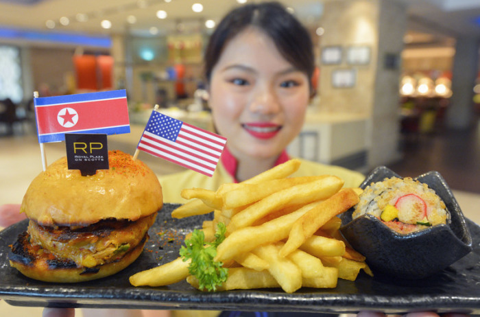 Eine Kellnerin eines Restaurants zeigt einen speziellen Hamburger, der aus Anlass des Treffens von US-Präsident Trump und Nordkoreas Machthaber Kim kreiert wurde. Foto: Kyodo/Dpa