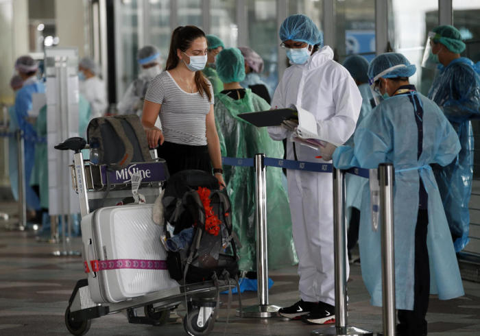 Eine Ausländerin wird bei ihrer Ankunft am internationalen Flughafen Suvarnabhumi in Bangkok vom medizinischen Personal ihres gebuchten ASQ-Hotels in Empfang genommen. Foto: epa/Rungroj Yongrit