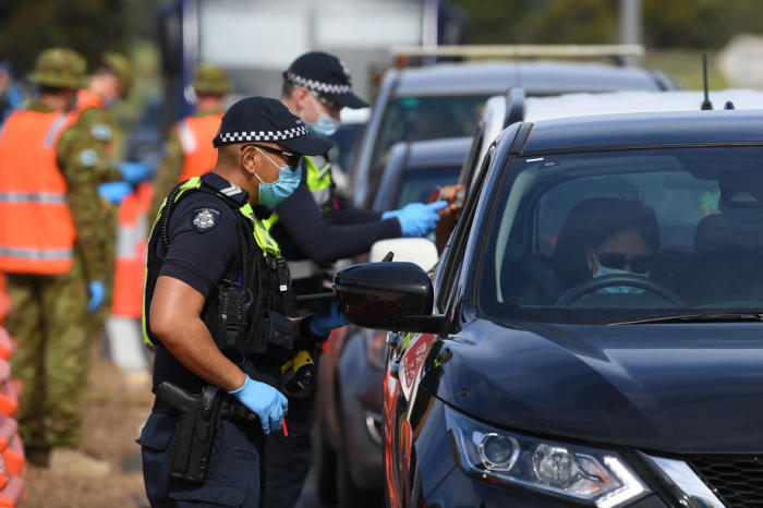 Die Polizei von Victoria und Mitarbeiter der australischen Verteidigungskräfte bei der Arbeit an einem Straßenkontrollpunkt in der Nähe von Donnybrook. Foto: epa/James Ross