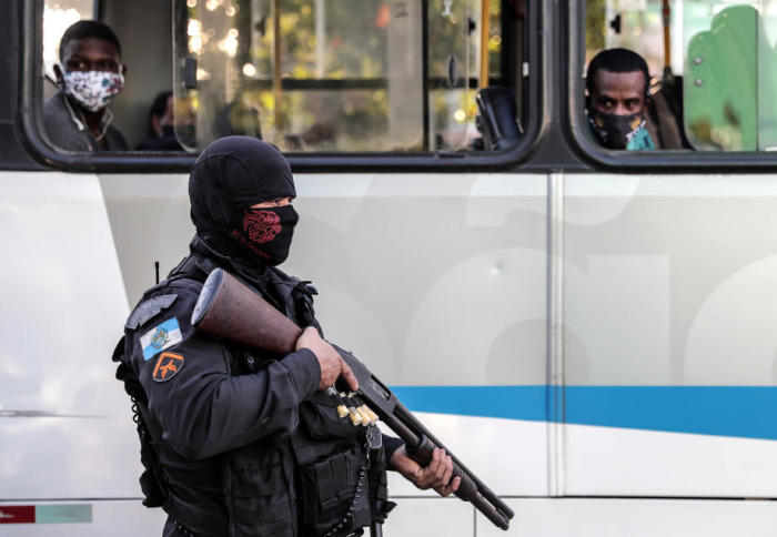 Zwei Buspassagiere beobachten einen Polizisten. Foto: epa/Antonio Lacerda