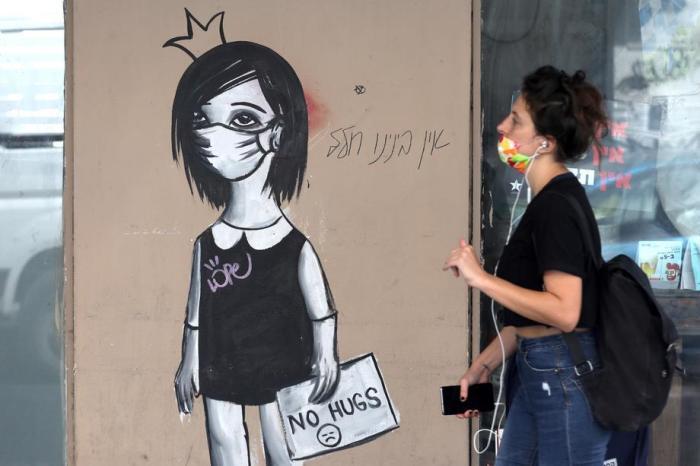 Eine Frau geht in Tel Aviv an einem Coronavirus-Graffiti vorbei. Foto epa/ABIR SULTAN