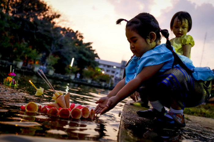 Zwei Kinder setzen ihre Krathong in einer Parkanlage in Bangkok ins Wasser. Foto: epa/Diego Azubel