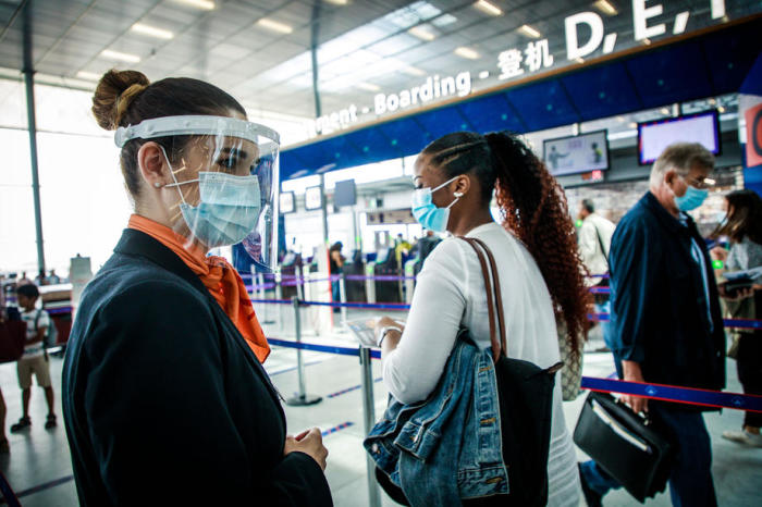 Eine Hostess, die eine Gesichtsmaske trägt, führt die Passagiere am Flughafen Orly in der Nähe von Paris. Foto: epa/Christophe Petit Tesson