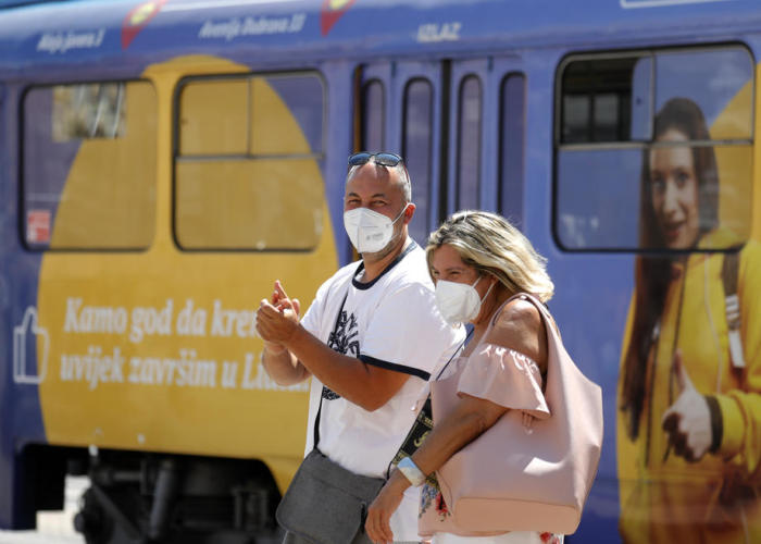 Ein Paar, das eine Gesichtsmaske trägt, geht in der kroatischen Hauptstadt Zagreb an einer Straßenbahn vorbei. Foto: epa/Antonio Bat