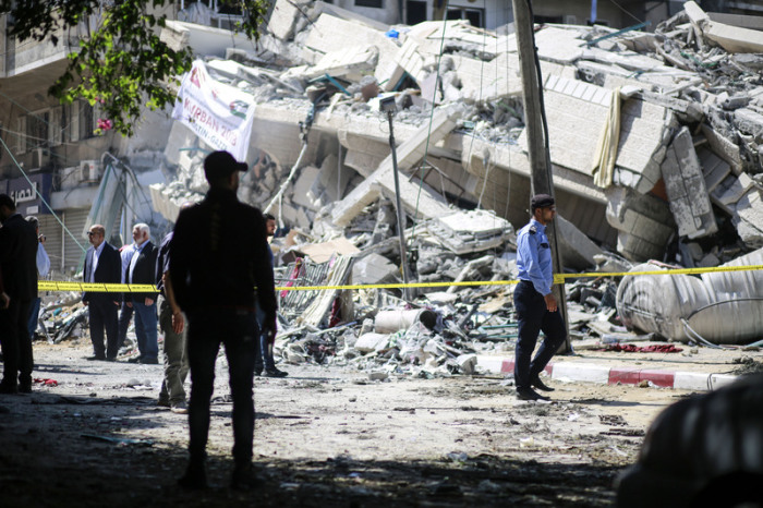 Polizisten und Einsatzkräfte stehen vor den Trümmern eines Gebäudes, welches bei israelischen Luftangriffen auf die Stadt zerstört wurde. Foto: Mohamed Zarandah/Quds Net News Via Zuma Wire/dpa