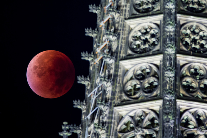 Der Mond erscheint während einer totalen Mondfinsternis neben einer der beiden Domspitzen rötlich. Foto: Rolf Vennenbernd/Dpa