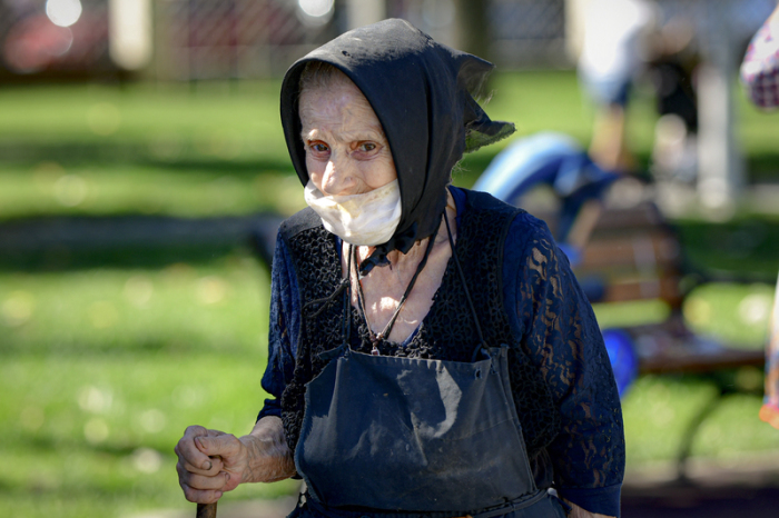 Eine ältere Frau mit einem improvisierten Mundschutz spaziert in Bukarest. Foto: Andreea Alexandru/Ap/dpa