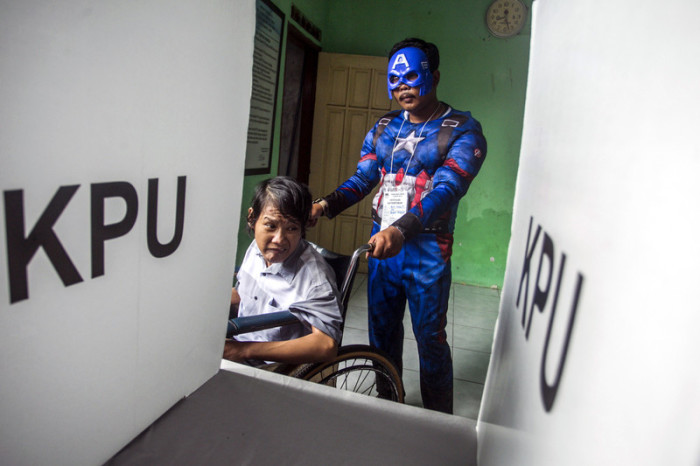 Wahlhelfer in Superheldenkostüm im indonesischen Surabaya. Foto: epa/Fully Handoko