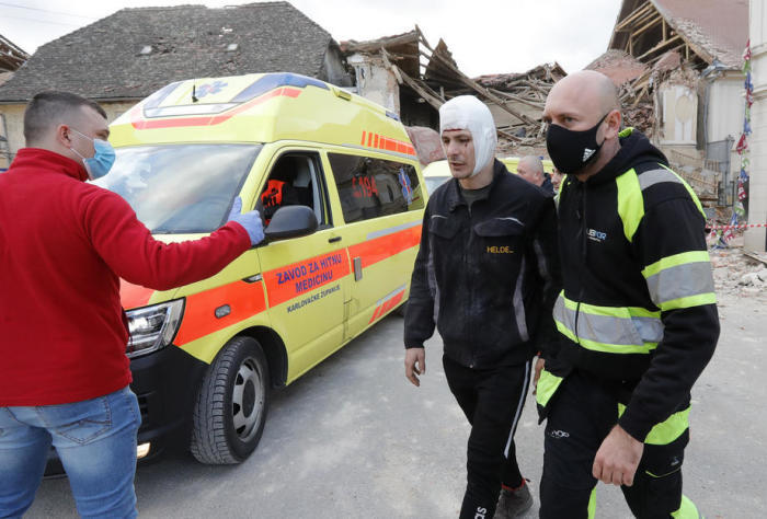 Ein Mann mit einer Kopfverletzung wird aus den bei einem Erdbeben in Petrinja beschädigten Gebäuden weggeführt. Foto: epa/Antonio Bat