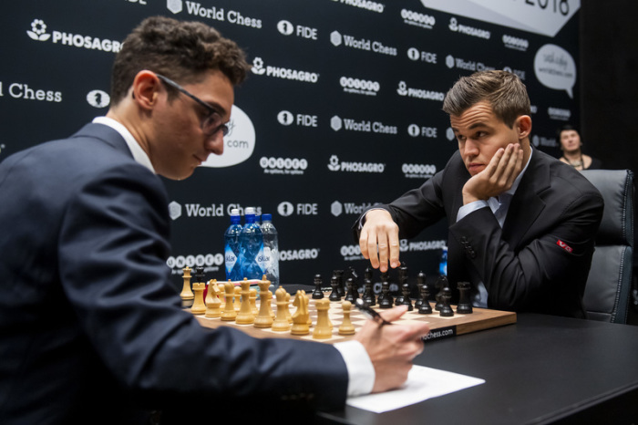 Magnus Carlsen (r) und Fabiano Caruana sitzen sich am Schachbrett gegenüber. Foto: Fredrik Varfjell/Bildbyran Via Zuma Press/dpa