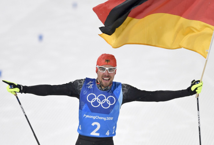 Schon 200 Meter vor dem Ziel bekam Großschanzen-Sieger Rydzek die Fahne mit auf den Weg. Foto: epa/Daniel Kopatsch