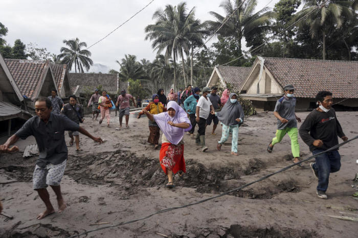 Bewohner des Dorfes Sumber Wuluh in Lumajang, Ost-Java, inspizieren ihr Dorf, das durch den Ausbruch des Mount Semeru mit Vulkanasche verschüttet wurde. Foto: epa/Ammar