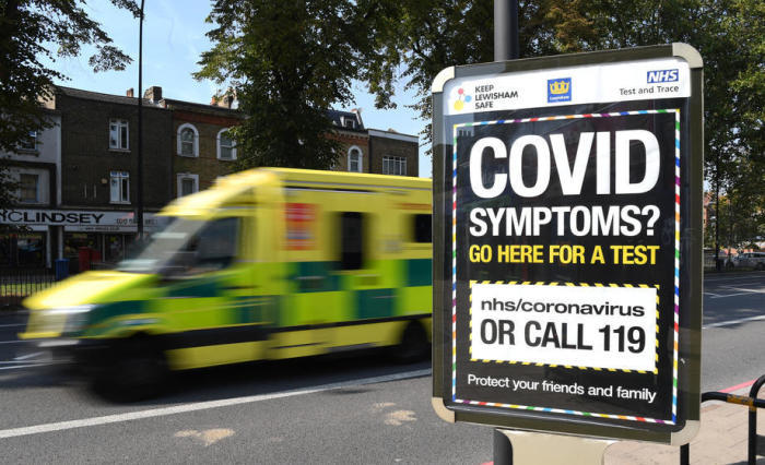 In London fährt ein Krankenwagen an einem Schild mit einer Covid-Helpline vorbei. Foto: epa/Facundo Arrizabalaga