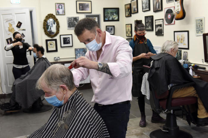 Friseur David Judge (C) trägt eine Gesichtsmaske, während er dem Kunden Robert Redmond (L) im Abner Browns Barbershop im Dubliner Vorort Rathmines einen Haarschnitt verpasst. Foto: epa/Bryan Meade