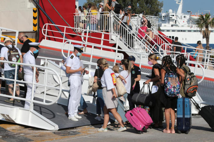 Beamte der griechischen Küstenwache überprüfen die Dokumente von Passagieren im Hafen von Piräus bei Athen. Foto: epa/Pantelis Saitas