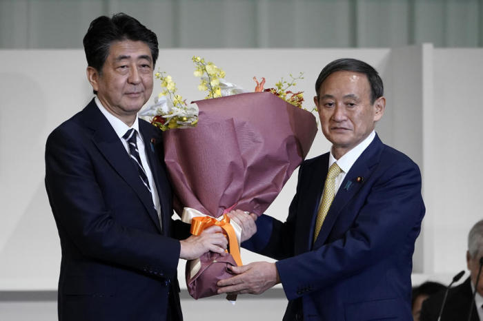 Der japanische Premierminister Shinzo Abe (L) überreicht dem Kabinettschef Yoshihide Suga (R) Blumen, nachdem Suga zum neuen Vorsitzenden der Regierungspartei Japans gewählt wurde. Foto: epa/Eugene Hoshiko