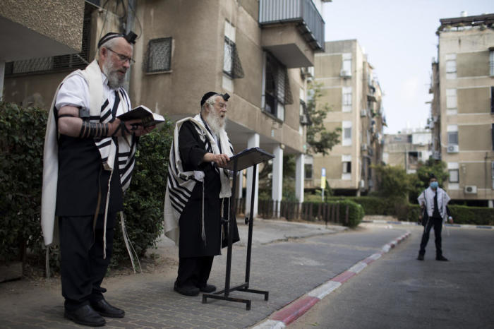 Ultra-orthodoxe Juden tragen einen Gebetsschal und beten ein Morgengebet vor einem Wohnhaus nach einer nächtlichen Ausgangssperre in der Stadt Bnei Brak. Foto: epa/Abir Sultan
