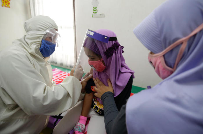 Ein Arzt im Schutzanzug impfen ein Mädchen in einem Impfstoffhaus in Depok, Indonesien. Foto: epa/Adi Weda