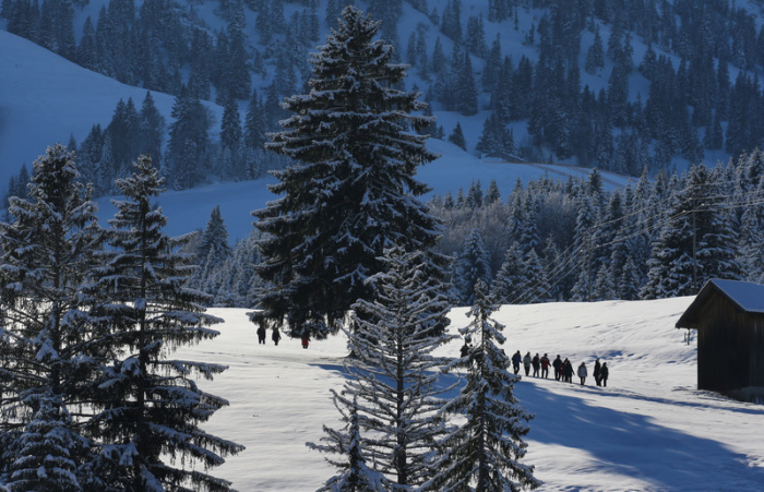 Eine Gruppe von Wanderern geht im Sonnenschein durch die schneebedeckte Landschaft. Foto: Karl-Josef Hildenbrand/Dpa