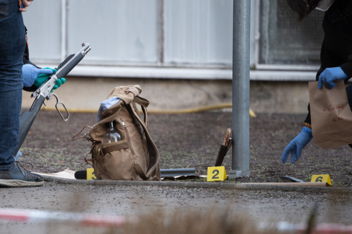 Polizeibeamte untersuchen eine Waffe und einen Geldbeutel am Gelände der Heidelberger Universität. Auf dem Campus der Heidelberger Universität hat es einen Amoklauf gegeben. Foto: Sebastian Gollnow/dpa