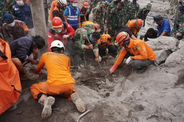 Helfer graben in einem vom Ausbruch des Mount Semeru in Lumajang betroffenen Gebiet nach der Leiche eines unter Vulkanasche begrabenen Opfers. Foto: epa/Ammar