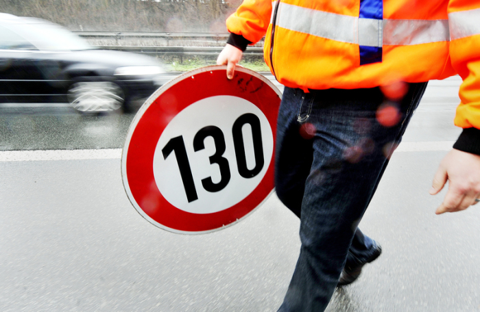 Ein Mitarbeiter der Autobahnmeisterei trägt auf der Autobahn 661 bei Frankfurt ein Schild zur Höchstgeschwindigkeit von 130 Stundenkilometern. Foto: Marius Becker/Dpa