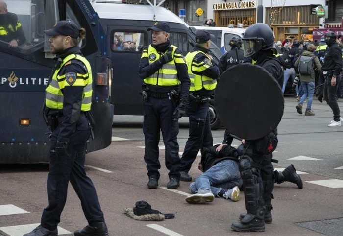 Polizisten nehmen einen Demonstranten fest, während Tausende von Menschen trotz eines Verbots gegen die von der niederländischen Regierung ergriffenen Corona-Maßnahmen protestieren. Foto: Peter Dejong/dpa