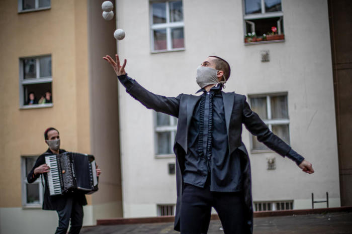 Mitglieder der zeitgenössischen Zirkusgruppe Cirk La Putyka treten in einem Innenhof auf, um die Anwohner in Prag zu unterhalten. Foto: epa/Martin Divisek