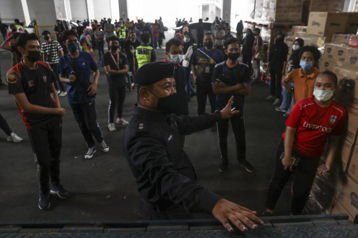 Ein Offizier der Royal Malaysian Police instruiert Arbeiter während einer Stichprobenkontrolle in einer Fabrik in Shah Alam in Selangor. Foto: epa/Fazry Ismail