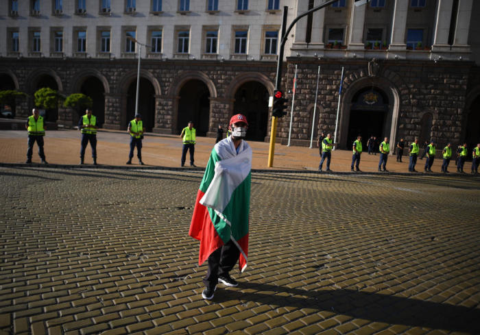 Ein in eine bulgarische Flagge gehüllter Mann schaut während eines regierungsfeindlichen Protests vor dem Ministerrat in Sofia zu. Foto: epa/Vassil Donev
