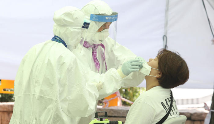 Medizinisches Personal in Schutzkleidung entnimmt im kommunalen Gesundheitszentrum Gangseo-gu in Seoul Proben von einem Studenten, um ihn auf das Coronavirus und die COVID-19-Krankheit zu testen. Foto: epa/Kim Chul-soo